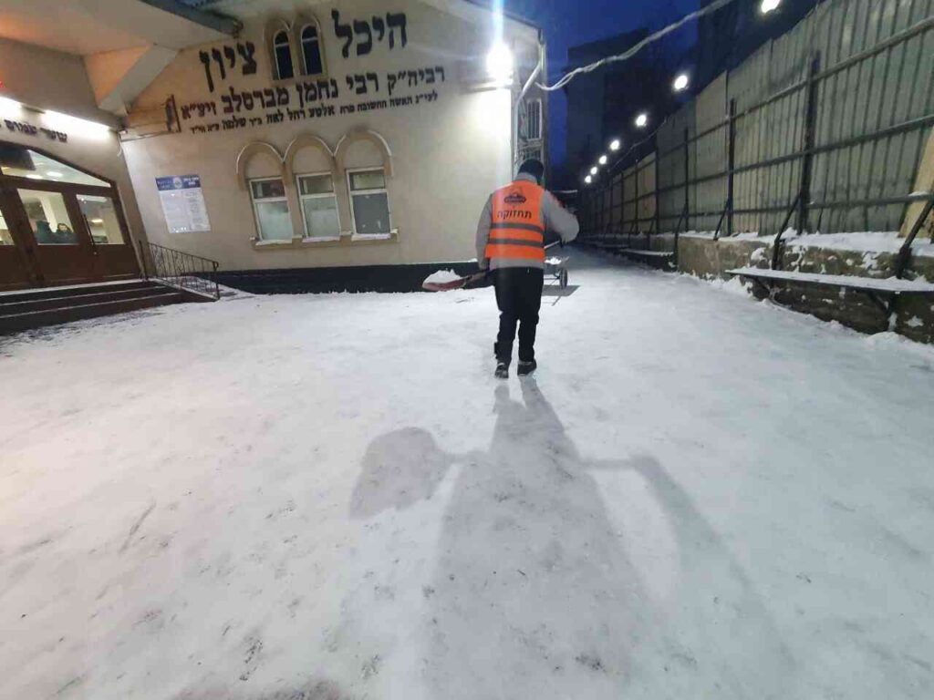 עובדי איחוד ברסלב באומן מפנים את השלג מדרכי הכניסה לציון